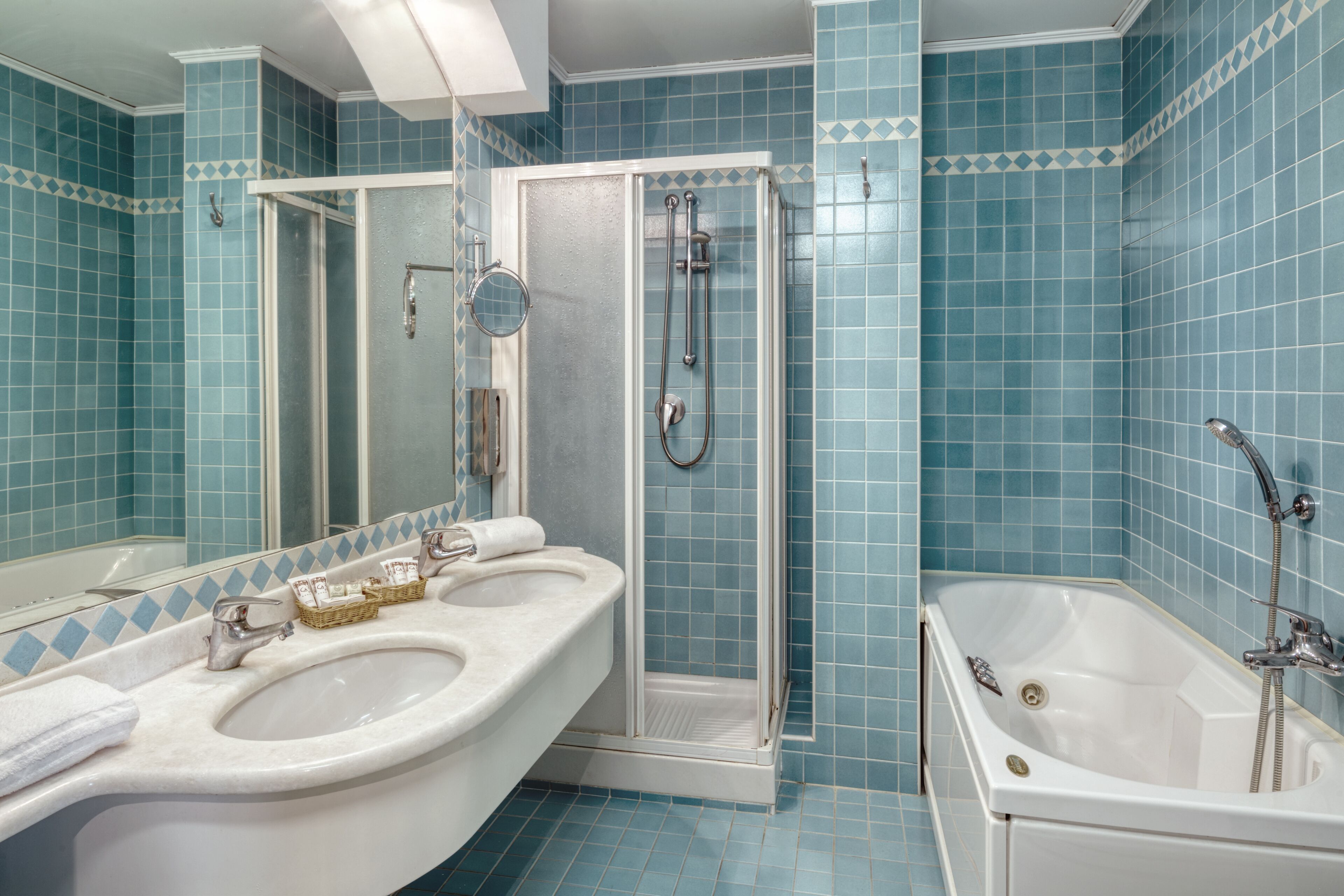 Un baño con ducha, dos lavamanos y bañera.