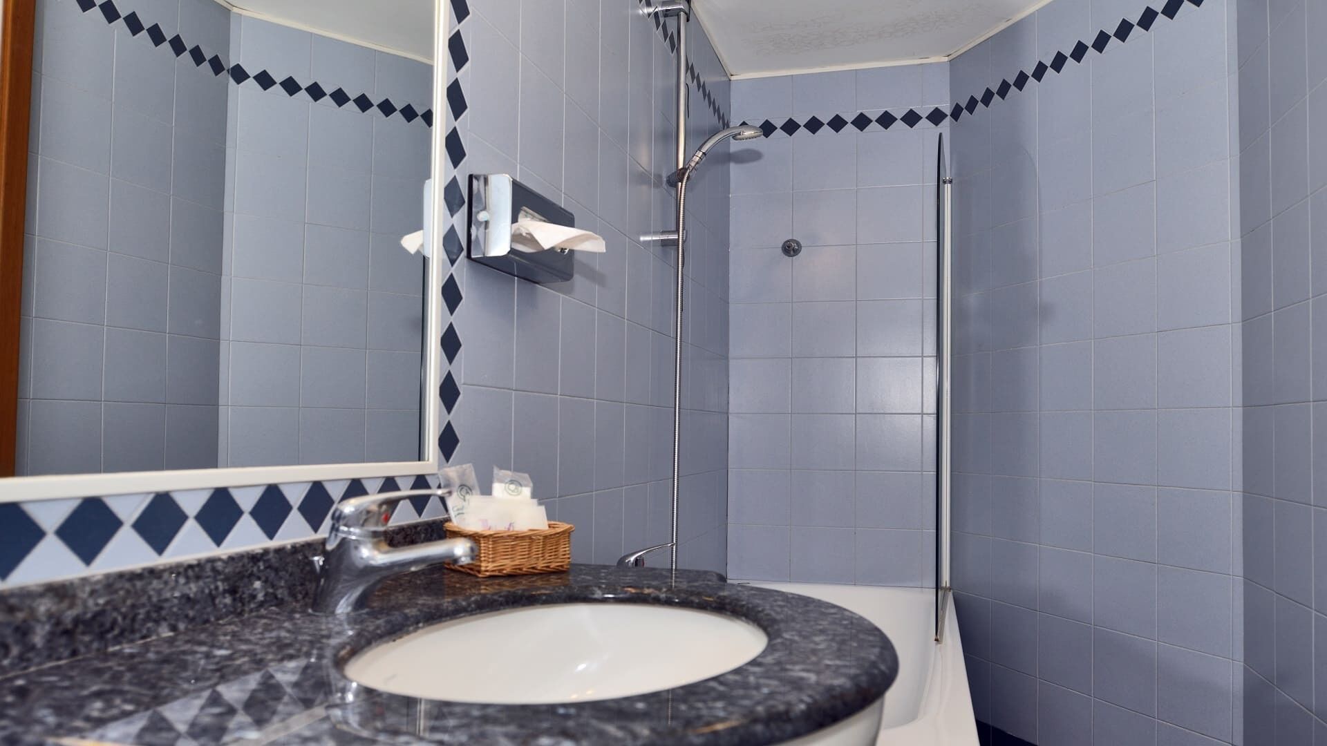 Un baño con lavamanos, espejo y ducha.