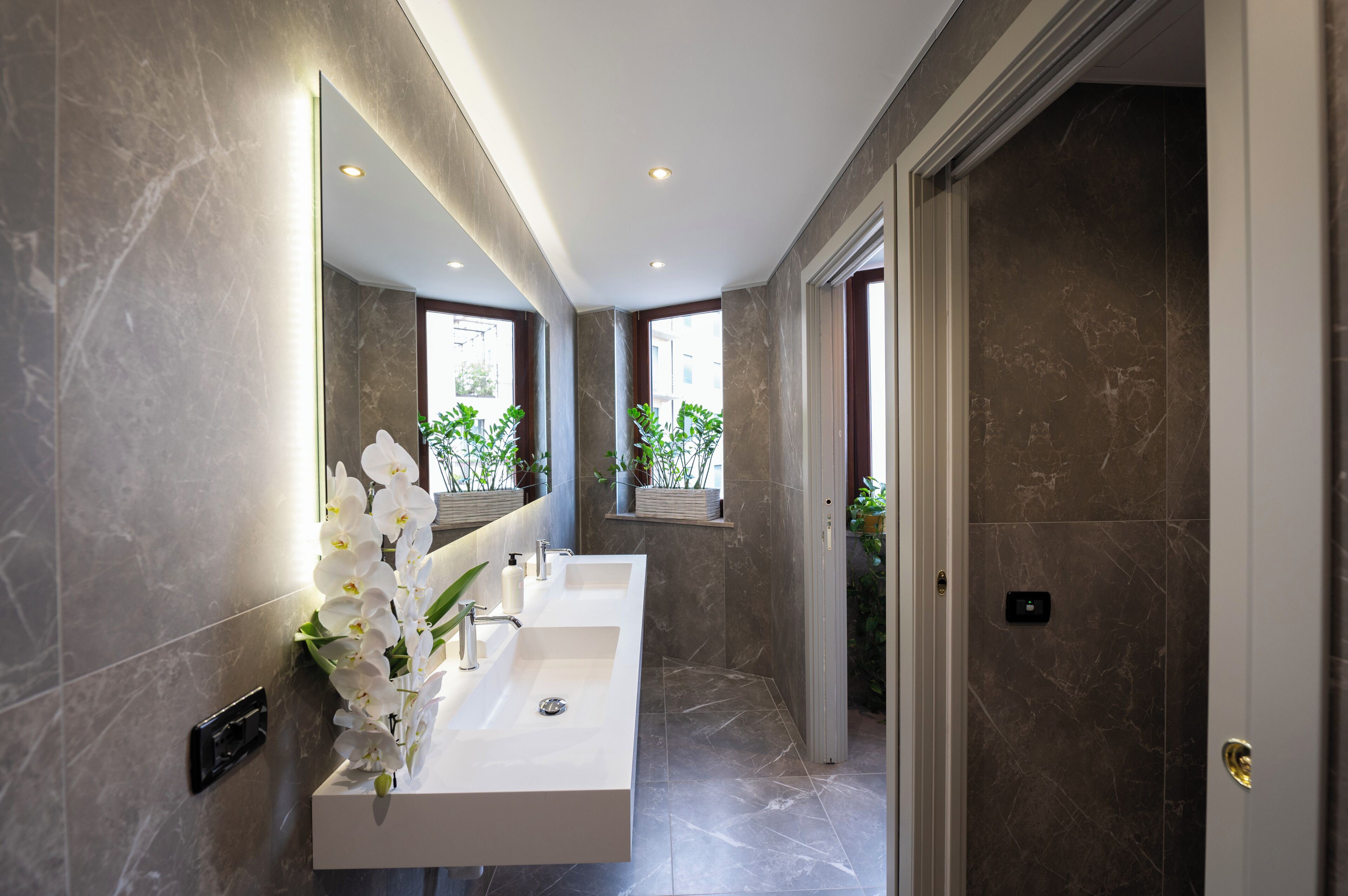 A modern bathroom with a large mirror, two sinks, and a shower area.