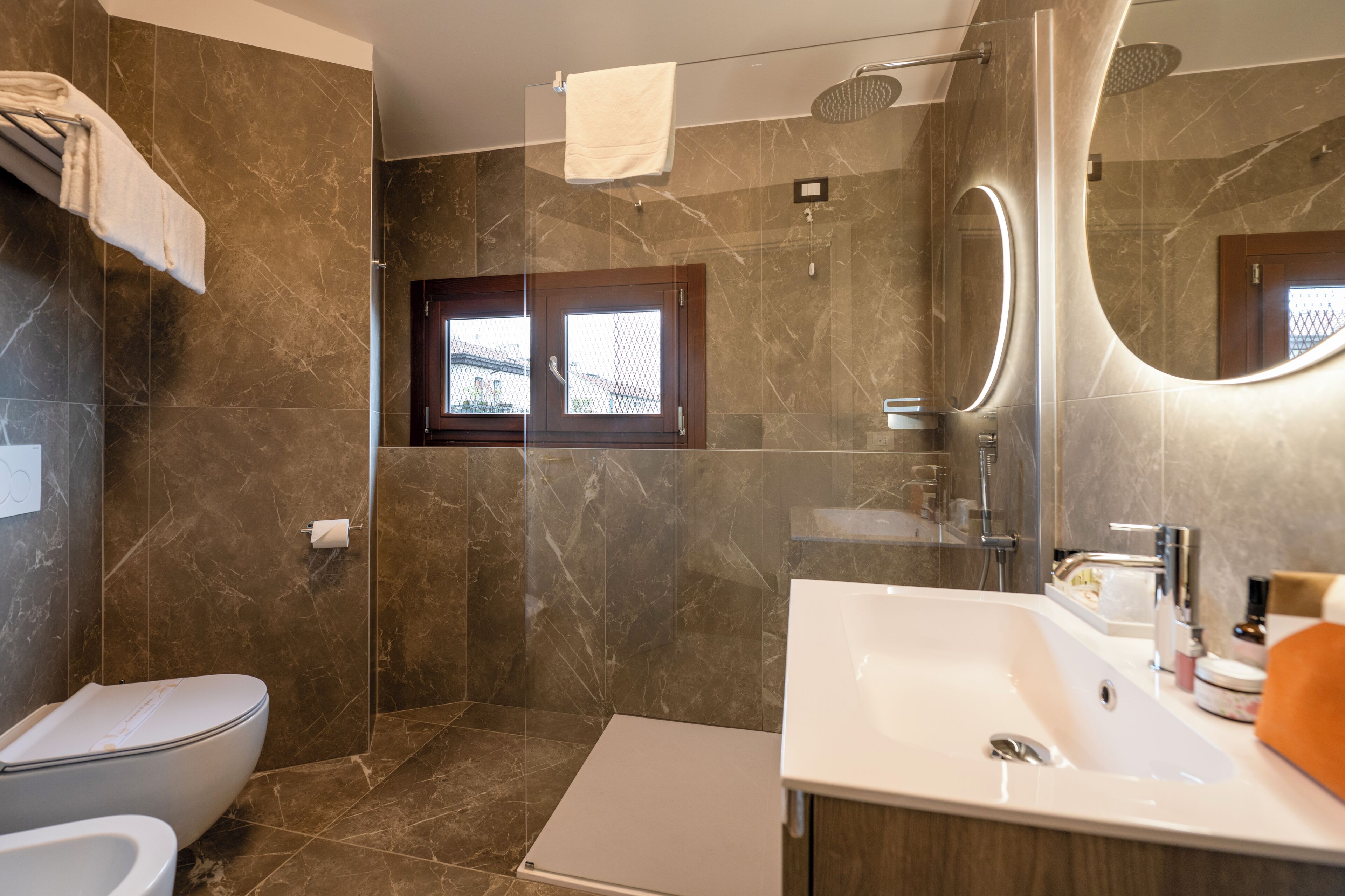 A modern bathroom with a shower, toilet, and sink.