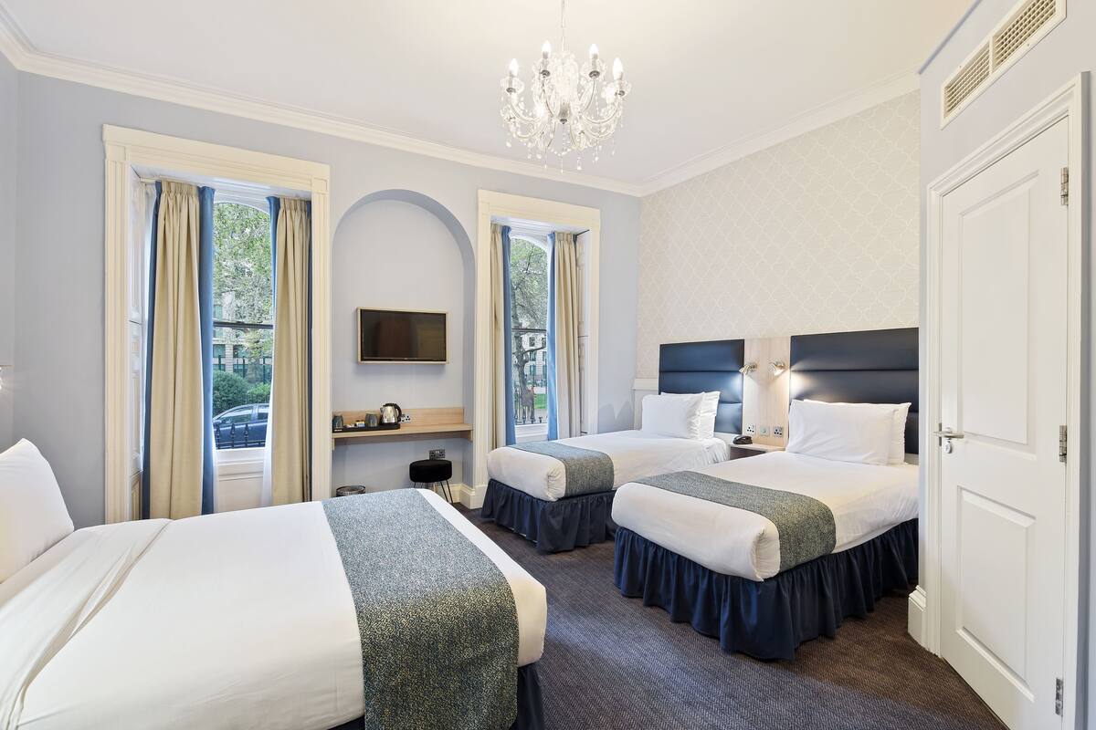 A hotel room with two beds, a chandelier, a flat-screen TV, and a view of the outdoors.