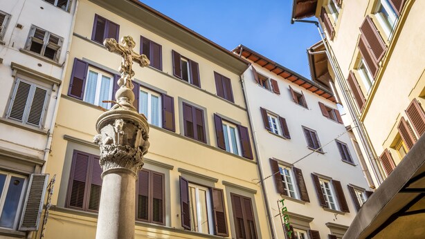 A building with multiple windows and a central column with a statue. - Hotel Ferretti (Florence)