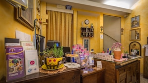 A reception desk with a yellow wall, a clock, and a framed picture. - Hotel Ferretti (Florence)