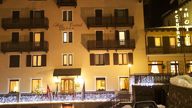 Un hôtel doté de nombreux balcons, une enseigne indiquant « Hôtel Centrale » et une façade bien éclairée.