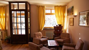 Un salon chaleureux avec des fauteuils à rayures, une table basse en bois et une grande fenêtre agrémentée de rideaux.