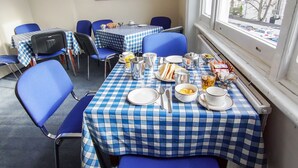 A dining area with checkered tablecloths, blue chairs, and various dining items.