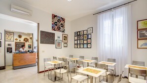 A hotel reception area with a wooden counter, white chairs, and framed artwork on the walls. - Hotel Nuova Italia (Florence)