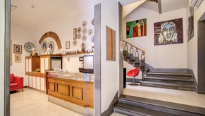 A modern kitchen with a wooden island, a red chair, and a staircase leading to a landing with artwork. - Hotel Nuova Italia (Florence)
