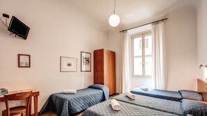 A hotel room with two beds, a desk, and a wardrobe. - Hotel Nuova Italia (Florence)