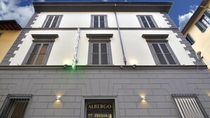 A building facade with the name "ALBERGO" and "NUOVAITALIA" signs, featuring a symmetrical window design and a central entrance. - Hotel Nuova Italia (Florence)