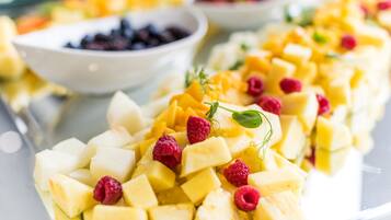 Ensalada de frutas con mango en cubos, frambuesas y una ramita de menta.