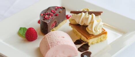 Un plato de postre con mousse de chocolate, una bola de helado, un trozo de pastel con caramelo y frambuesas.