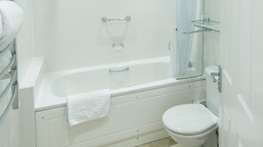 A bathroom with a white bathtub, a toilet, and a glass shower enclosure. - The Barnstaple Hotel (Barnstaple)