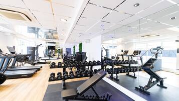 A modern gym with various exercise equipment, including treadmills, dumbbells, and weight benches.