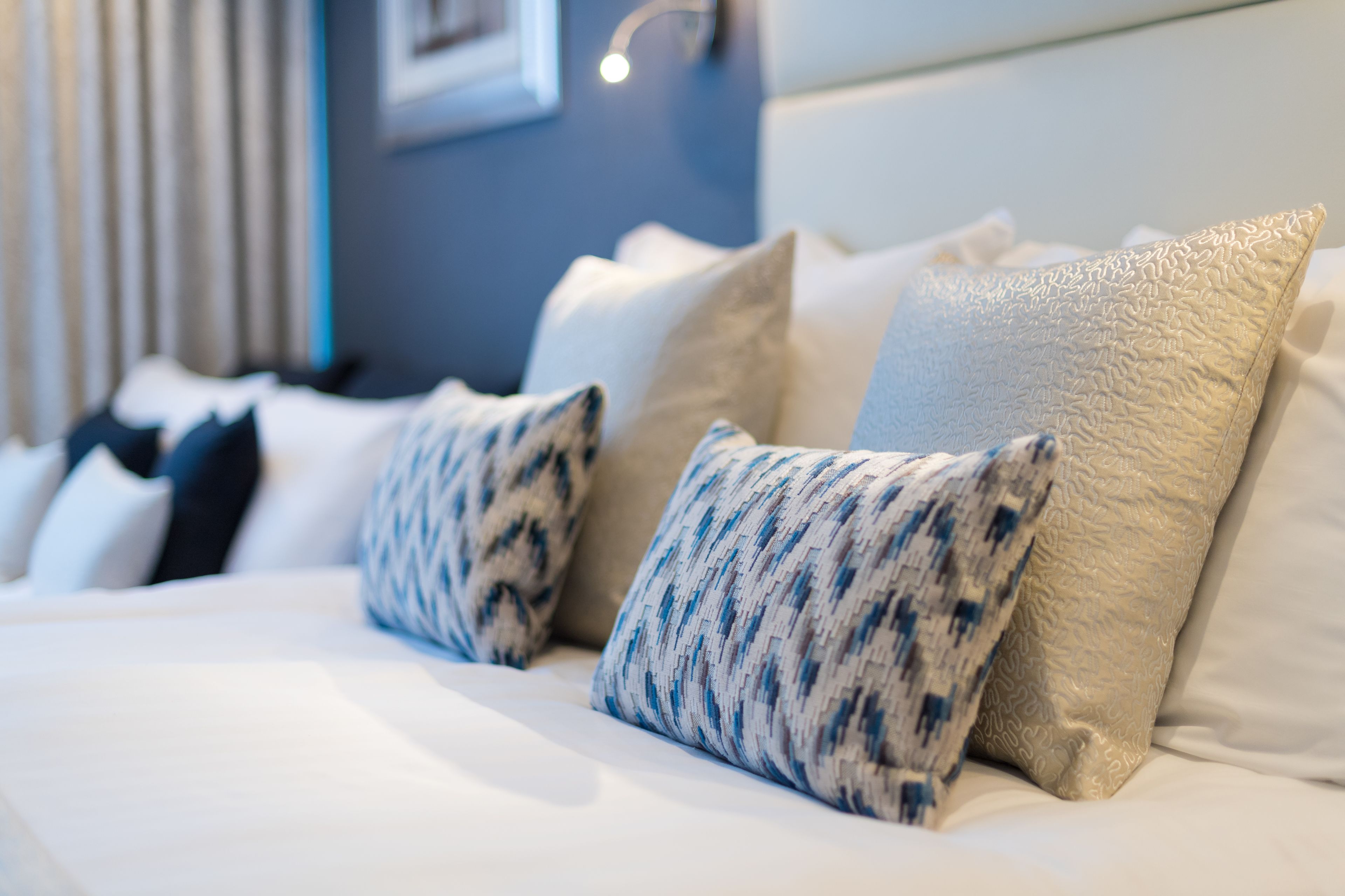 A neatly made bed with white linens and patterned pillows.