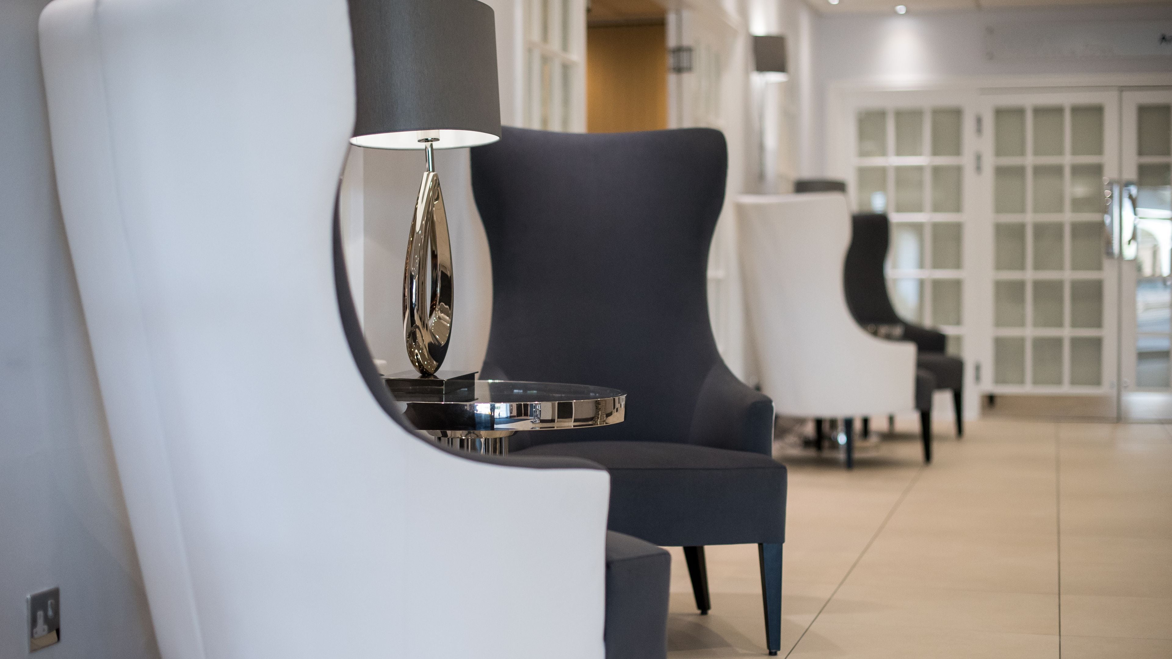 A modern hotel lobby with contemporary chairs and a sleek floor lamp.