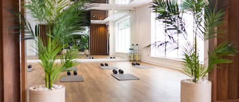 A spacious room with wooden flooring, large windows, and potted plants.