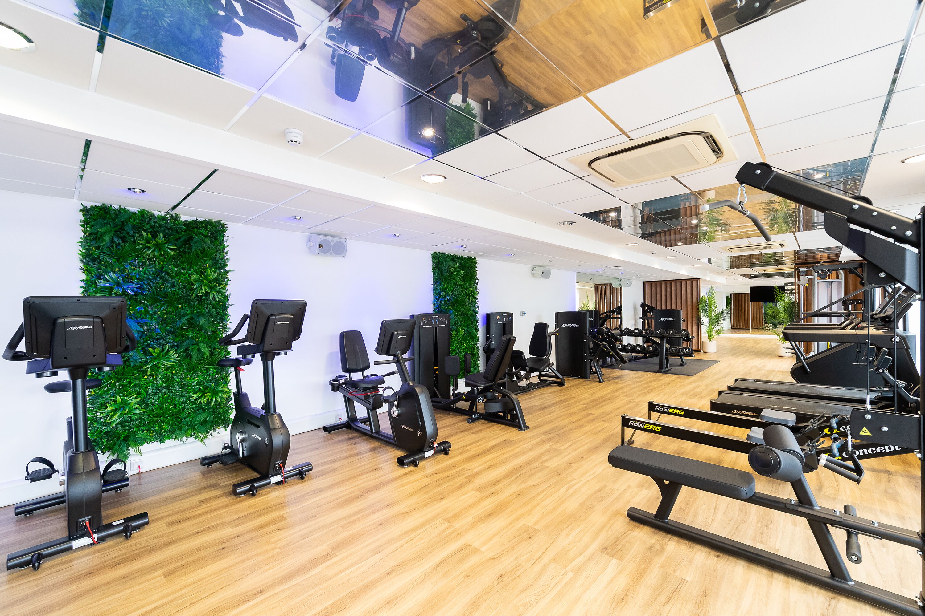 Ett gym med olika typer av träningsutrustning, inklusive löpband, motionscyklar och styrketräningsmaskiner.