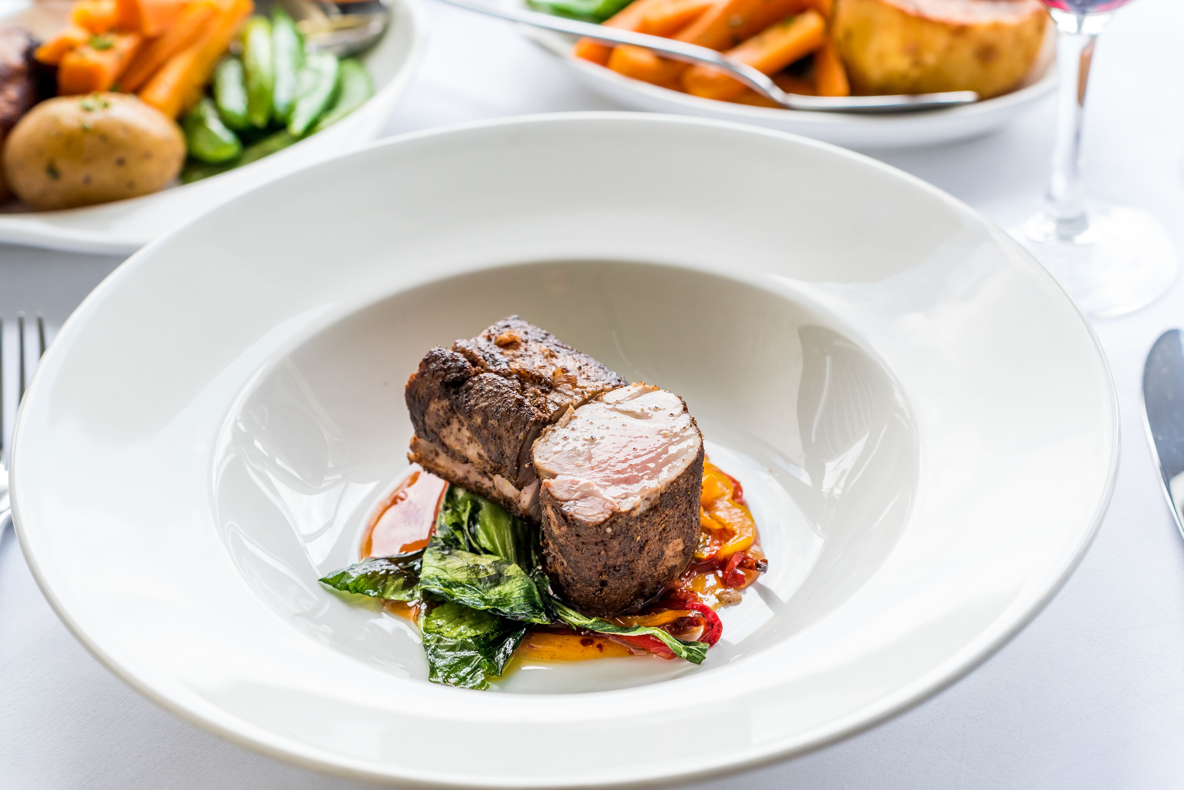Une assiette contenant un morceau de viande, des légumes et une sauce.