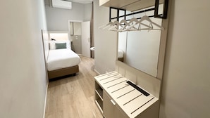 Una habitación de hotel moderna con una cama, armario vestidor y espejo.