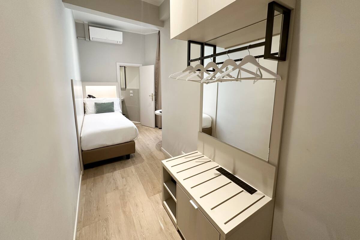A modern hotel room with a bed, a walk-in closet, and a mirror.