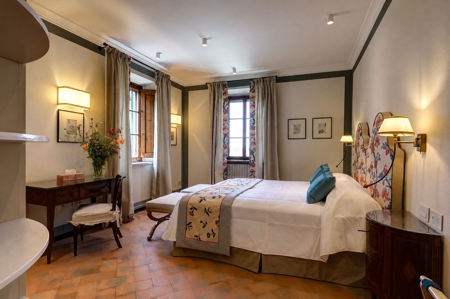 Ein Hotelzimmer mit Bett, Schreibtisch, Stuhl und einem Fenster mit Vorhängen.