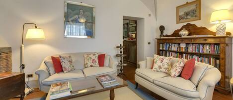 A living room with two sofas, a coffee table, a bookshelf, and a painting on the wall.