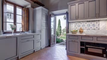 A kitchen with grey cabinets, a tiled backsplash, and a view of the outdoors.
