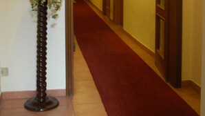 En hall med ett rött mattgolv, trädörrar och inramade konstverk på väggarna.