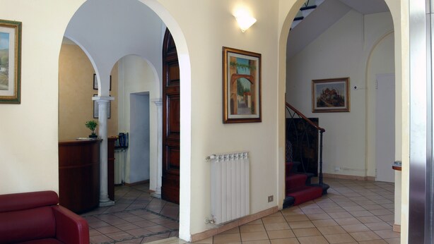 En rymlig hall med välvda dörröppningar, en röd soffa och en trappa.