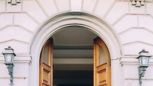 An arched doorway with wooden doors, a metal gate, and a sign with a symbol. - Hotel Cordova (Florence)