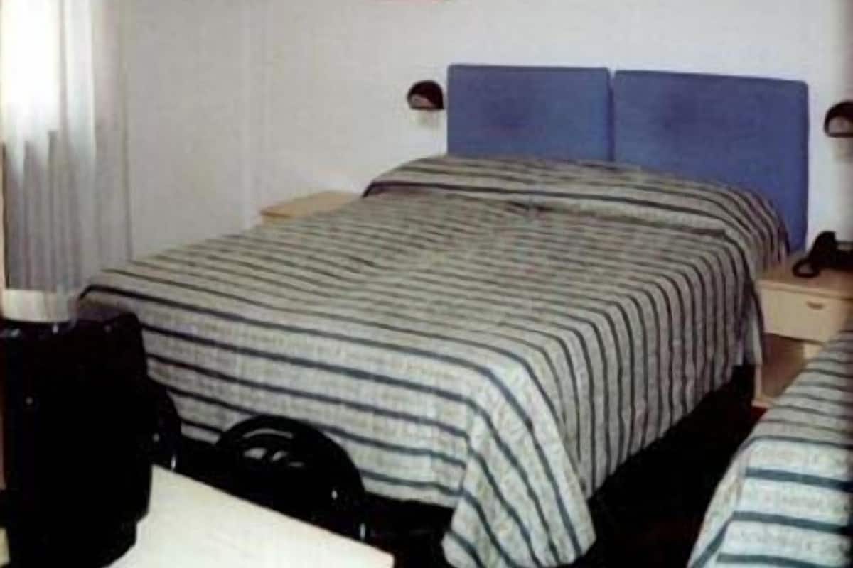 A hotel room with a bed, a nightstand, and a lamp.
