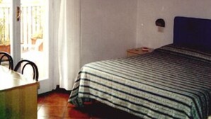 A bedroom with a bed, a nightstand, a chair, and a window with curtains. - Hotel Cordova (Florence)
