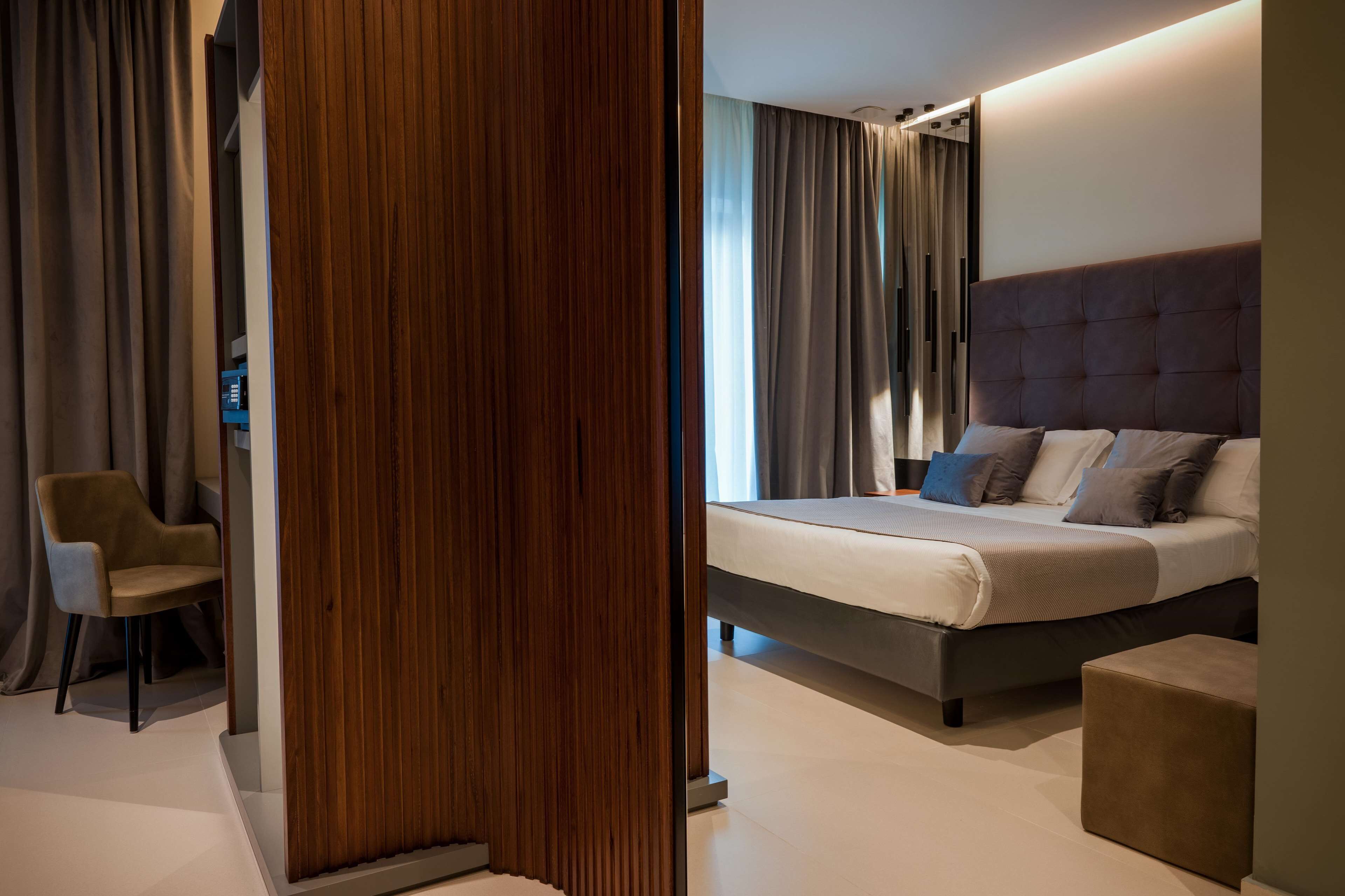 Een moderne slaapkamer met een groot bed, een houten scheidingswand en een stoel.