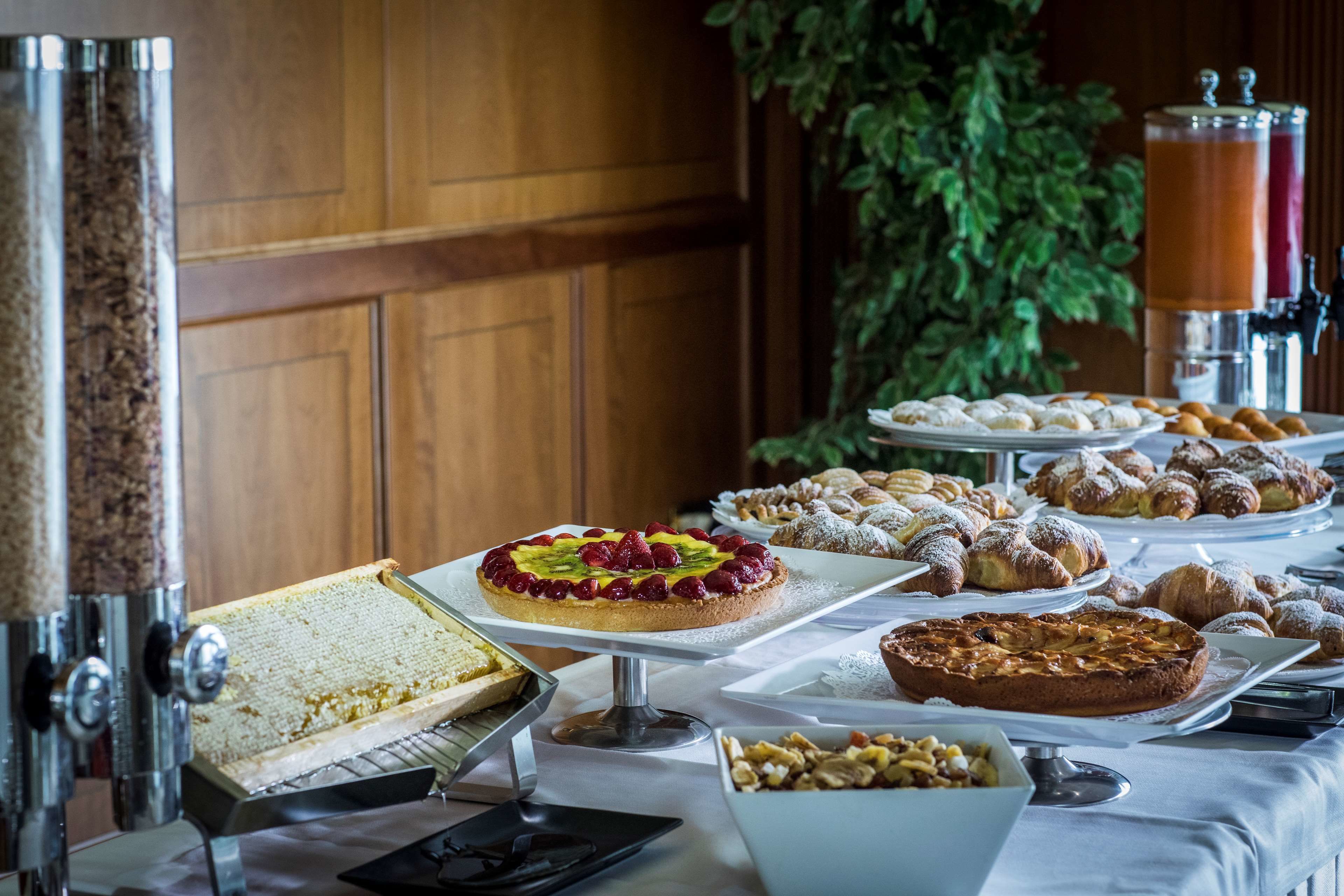 Mesa de buffet com diversos doces e sobremesas, incluindo torta de fruta e croissants.