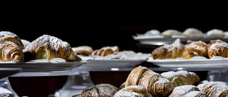 Variedad de pasteles, incluyendo croissants, dispuestos en bandejas.