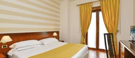 A hotel room with a bed, nightstands, a desk, and a chair.