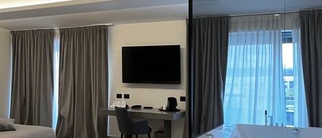Una habitación de hotel moderna con cama, escritorio, televisor y zona de comedor.