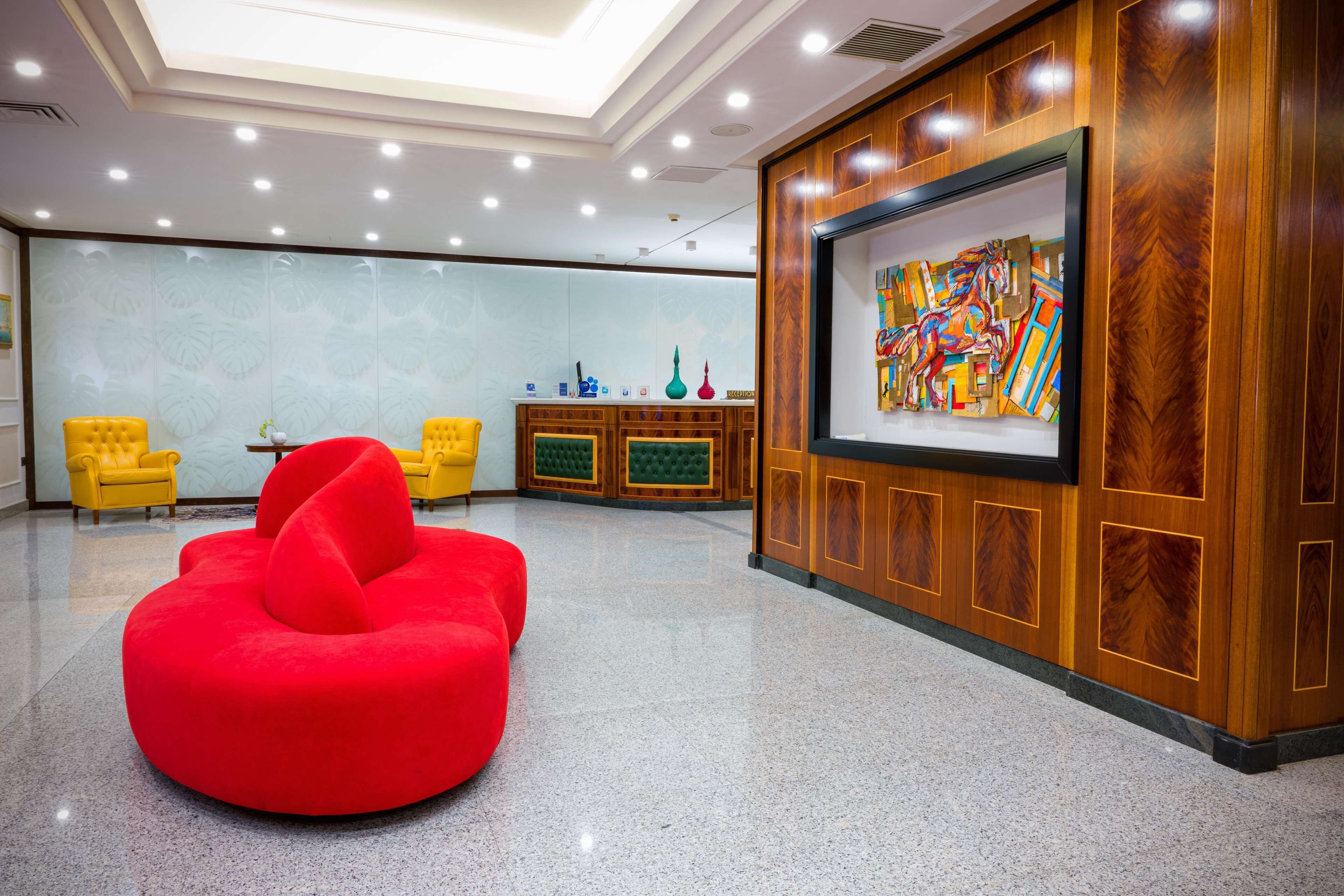 A lobby with a red bean bag chair, wooden reception desk, and a large abstract painting.