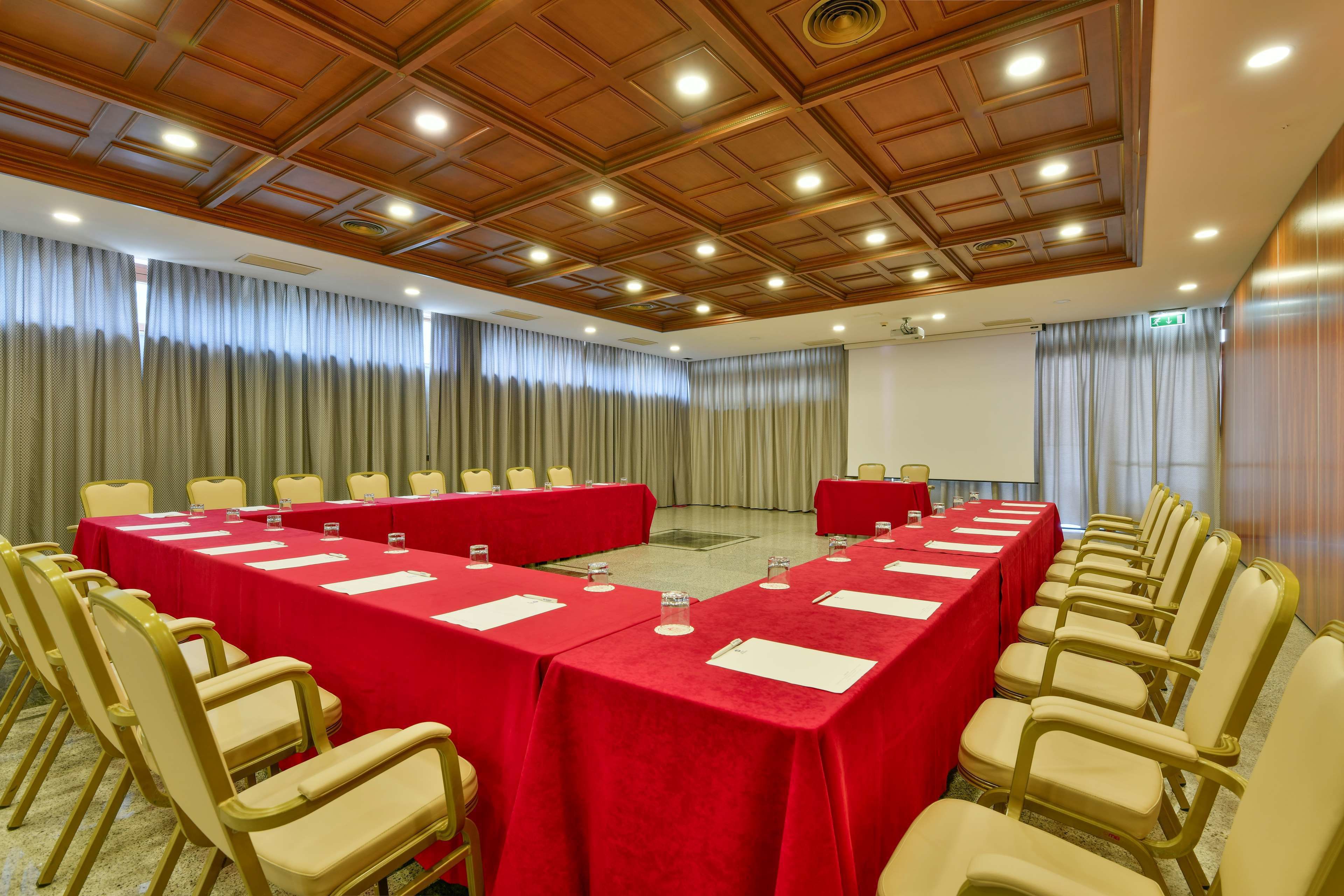 A conference room with a long table, chairs, and a red tablecloth.