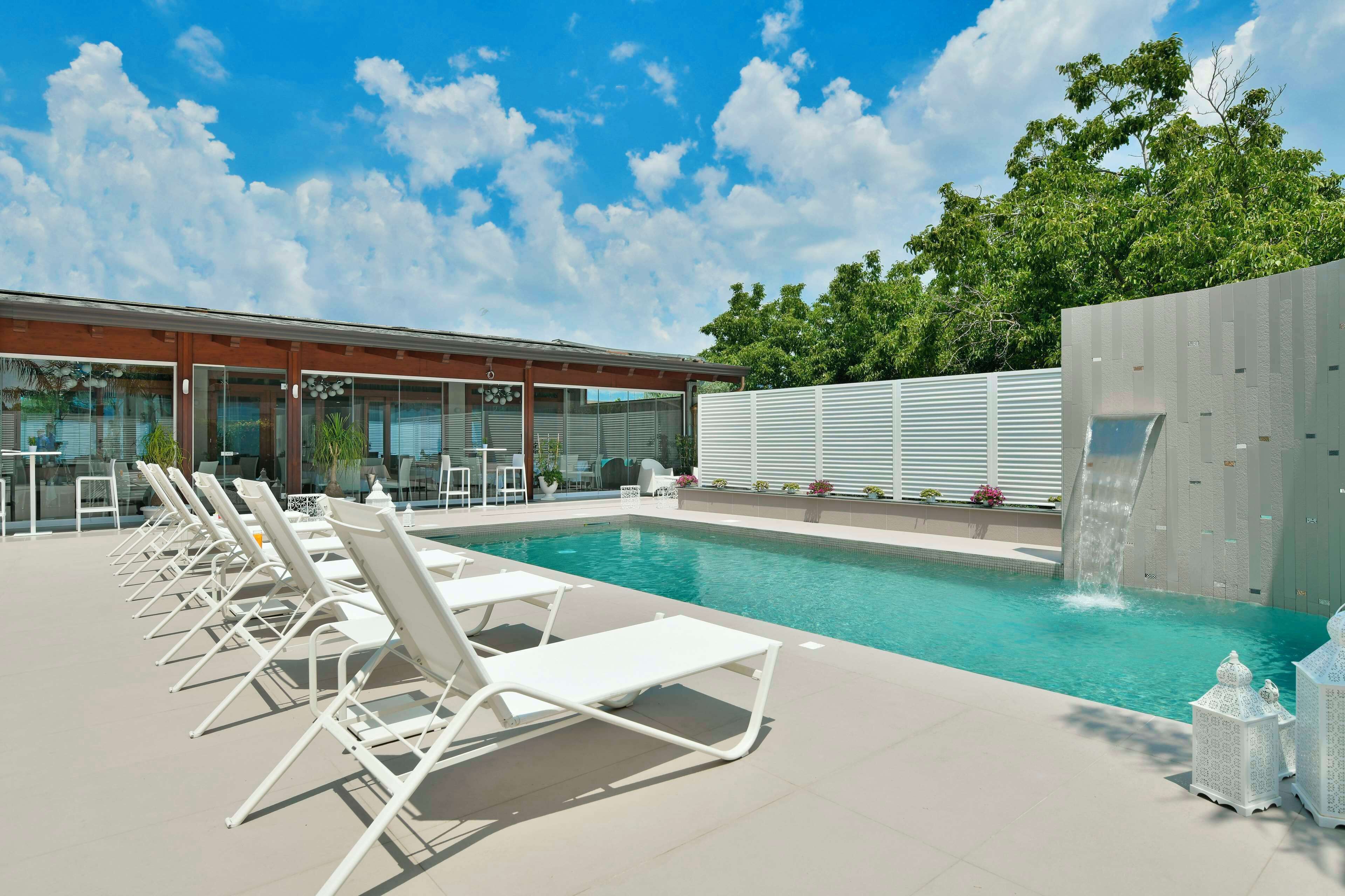 A swimming pool with lounge chairs and a waterfall feature.