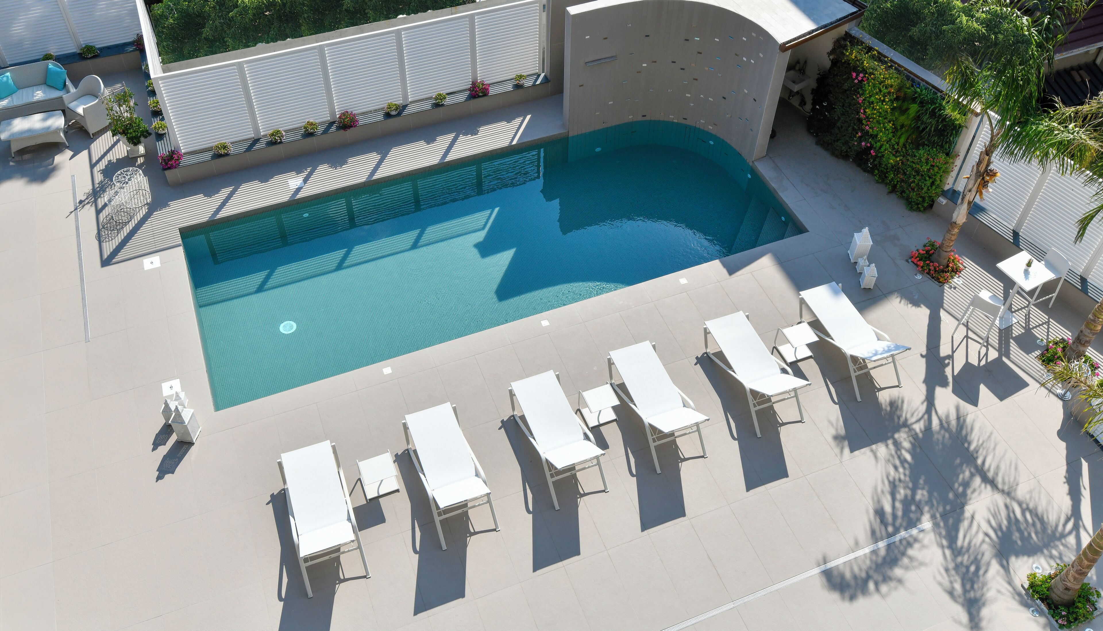Ein Pool auf dem Dach mit Liegestühlen und Kübelpflanzen.
