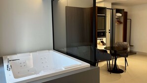 Une salle de bain moderne dotée d’une grande baignoire, d’une douche à parois de verre et d’un petit coin repas avec une table et des chaises.