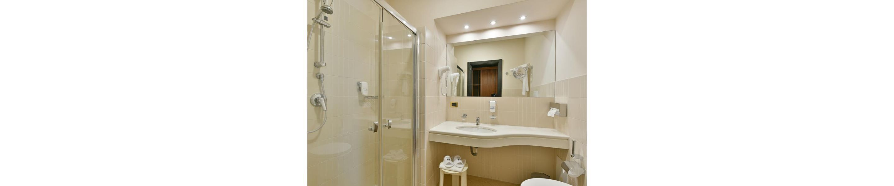 Un baño moderno con cabina de ducha de vidrio, lavamanos con espejo e inodoro.