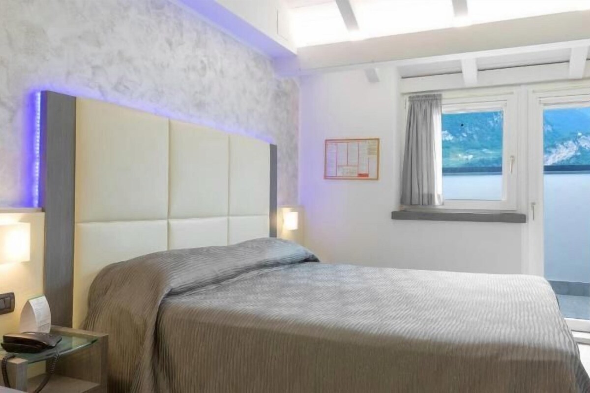 Une chambre à coucher avec un lit, une table de chevet et une vue sur l’extérieur par une fenêtre.
