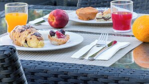 An outdoor dining area with wicker chairs and a table set for breakfast.