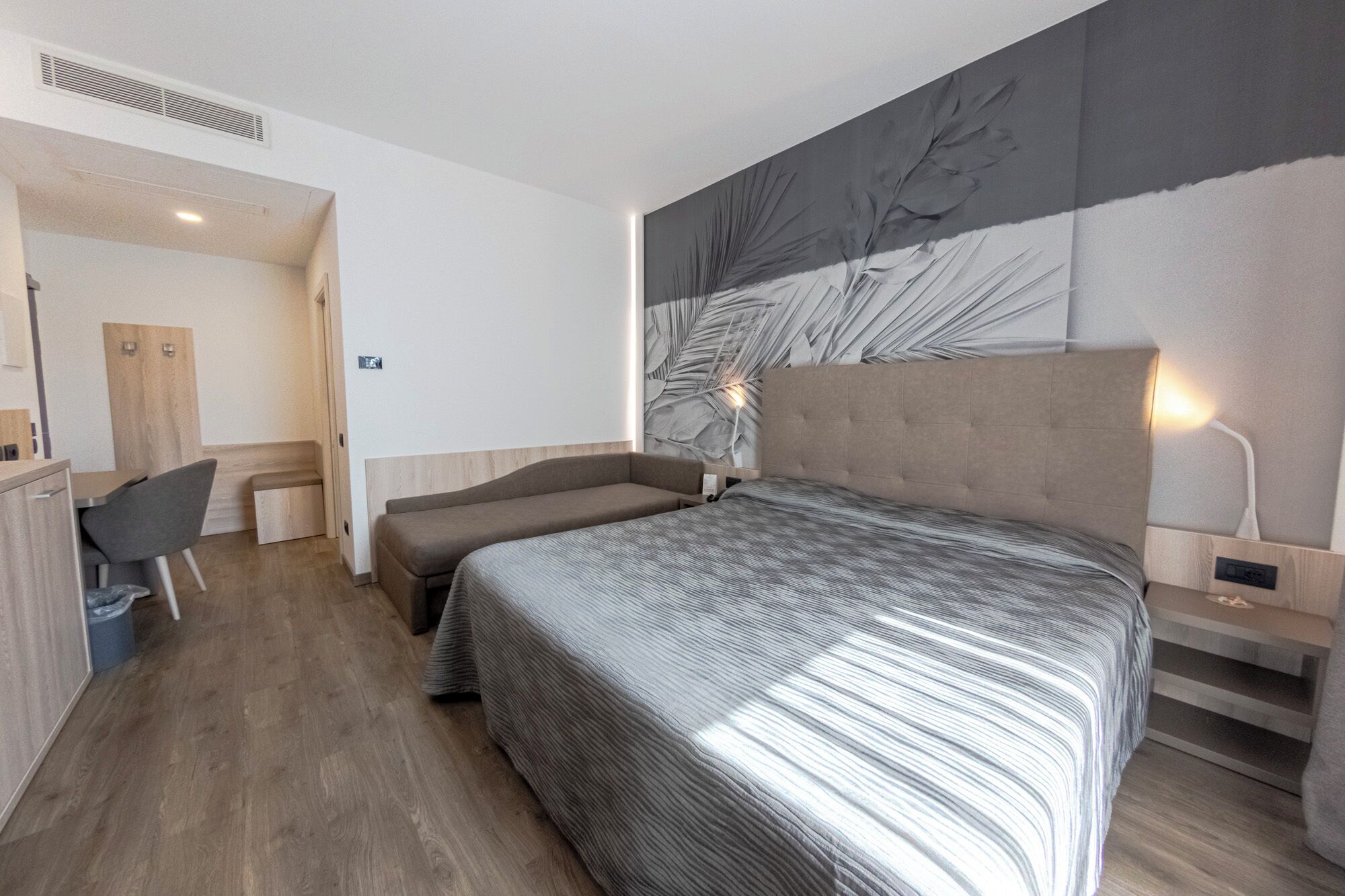 Een moderne hotelkamer met een groot bed, een bureau en een stoel.