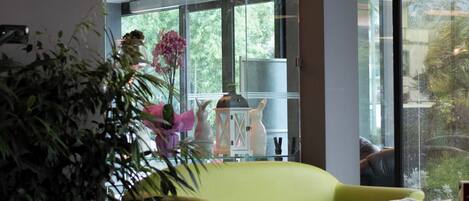 A modern interior with a green sofa, a white ottoman, and a large potted plant.