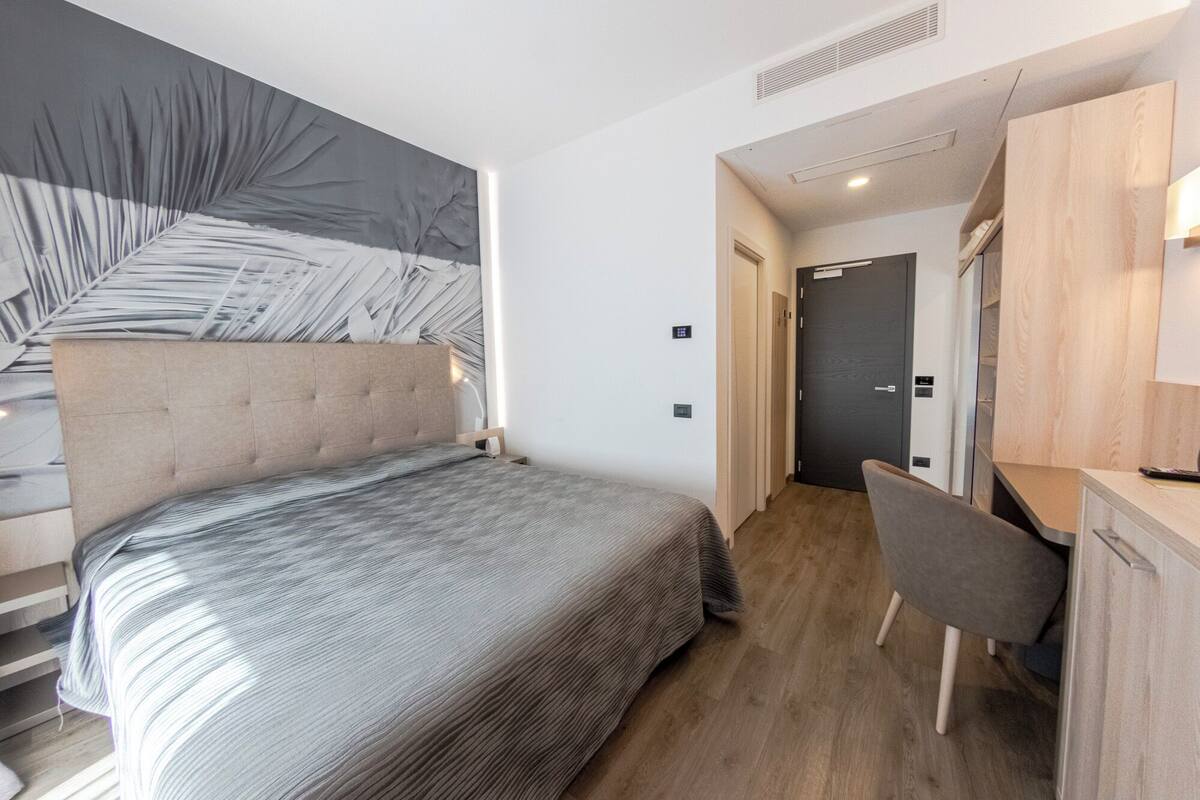 Een moderne hotelkamer met een bed, bureau en stoel.