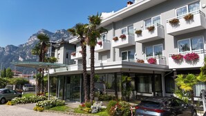A multi-story hotel with balconies, a covered entrance, and a mountain backdrop.
